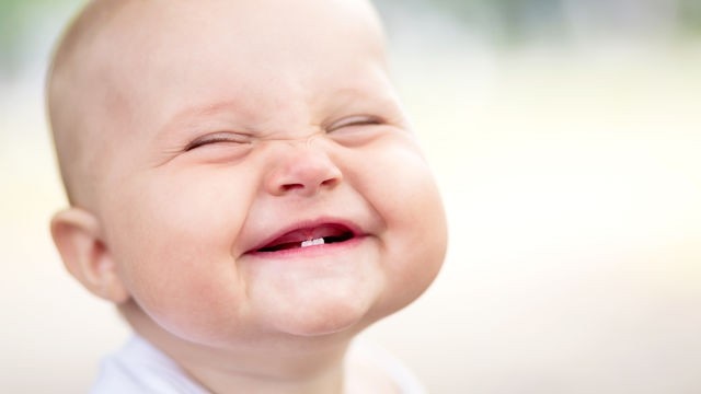 Baby lächelt und zeigt seine ersten Zähne