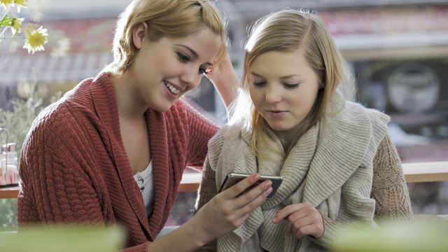 Zwei Frauen, die etwas auf ihrem Handy überprüfen