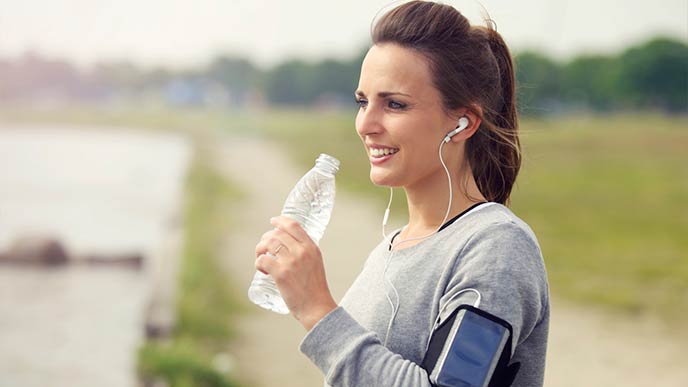 Frau treibt Sport und trinkt Wasser aus einer Flasche