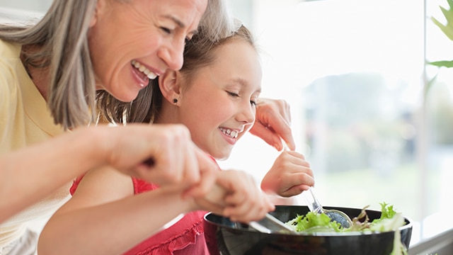Frau, die mit ihrem versteckten Salat kocht